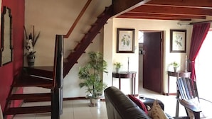 A spacious living area with a wooden staircase, a black leather sofa, and a dining table. - Benka Lifestyle (Lobamba)