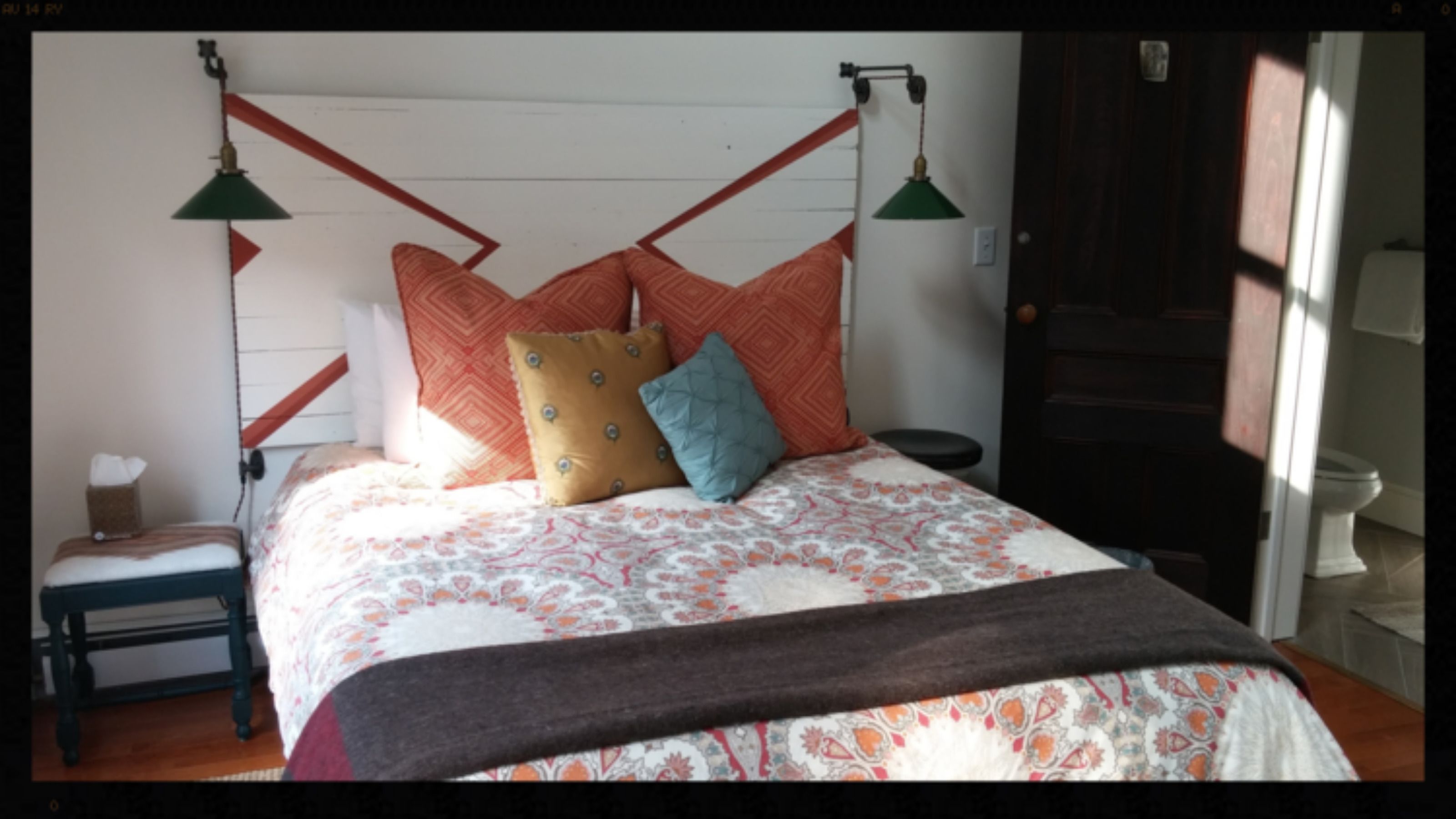 A bedroom with a bed, pillows, a bedside table, and a lamp.