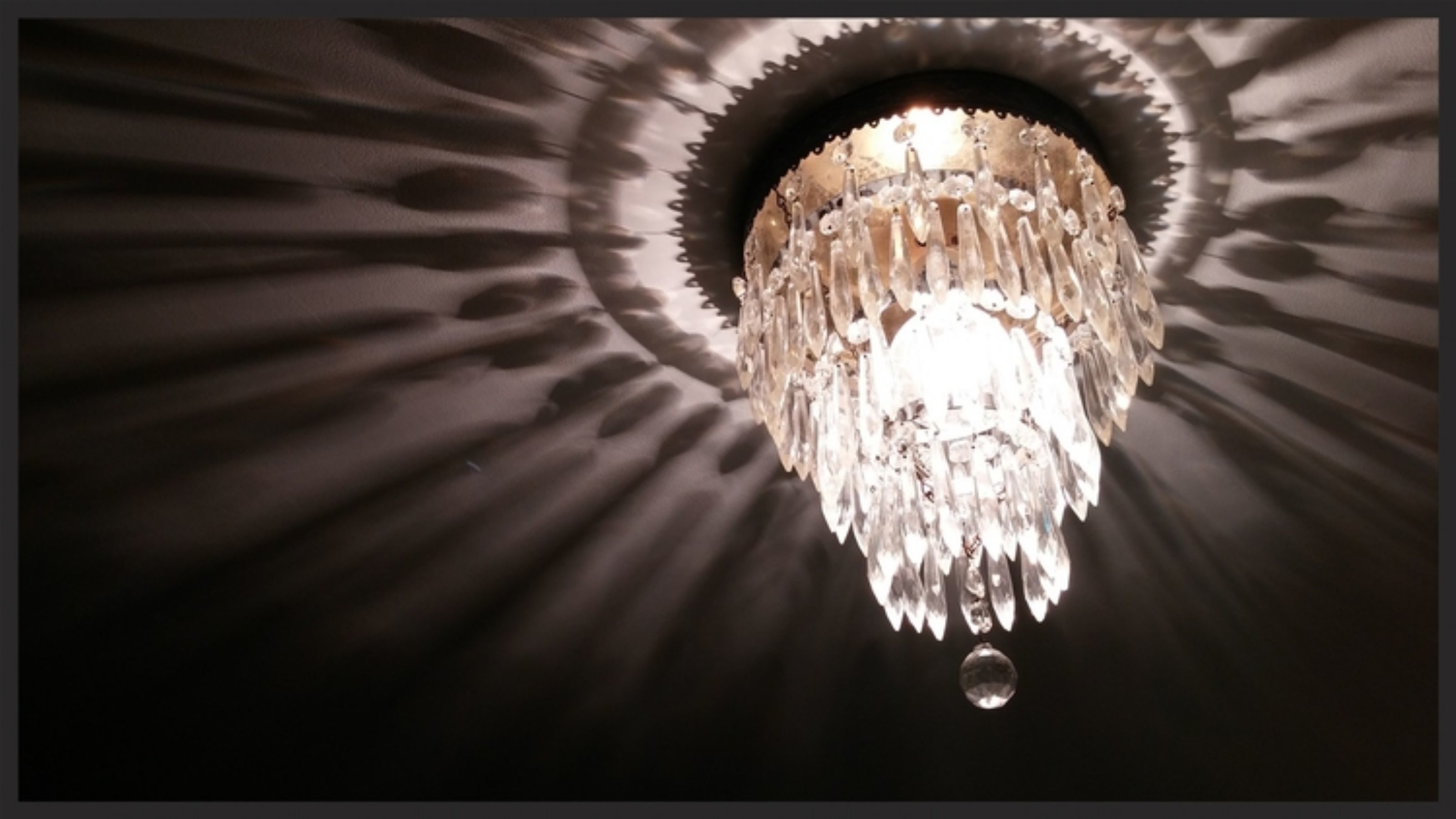A chandelier with multiple crystal elements hanging from a circular ceiling fixture.