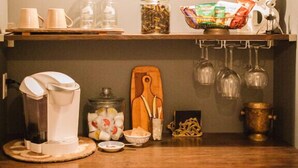 A kitchen counter with a coffee maker, jars, and a cutting board. - Burdett House Bed & Breakfast (Burdett)