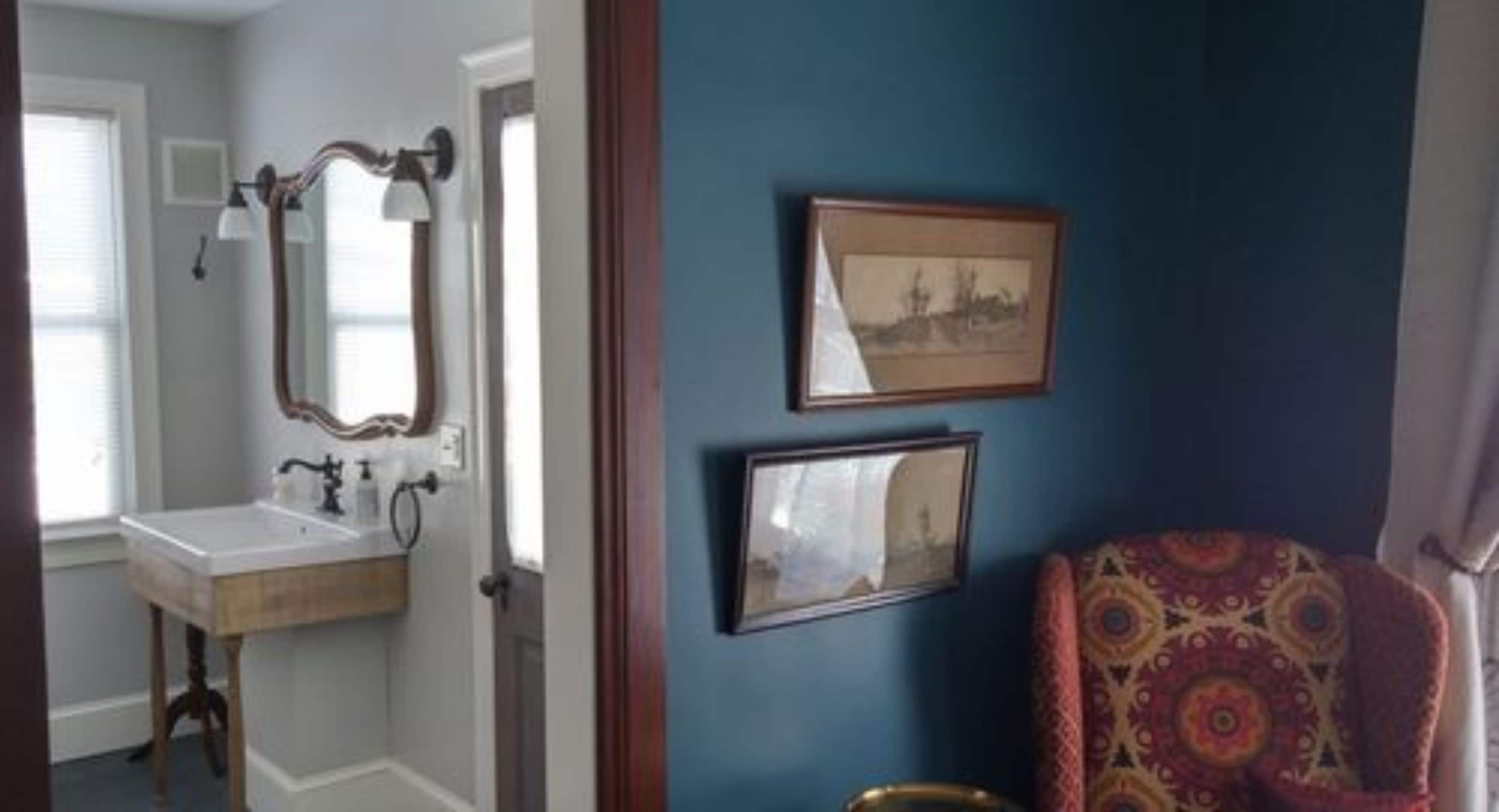 A room with a wooden vanity, a mirror, and two framed pictures on the wall.