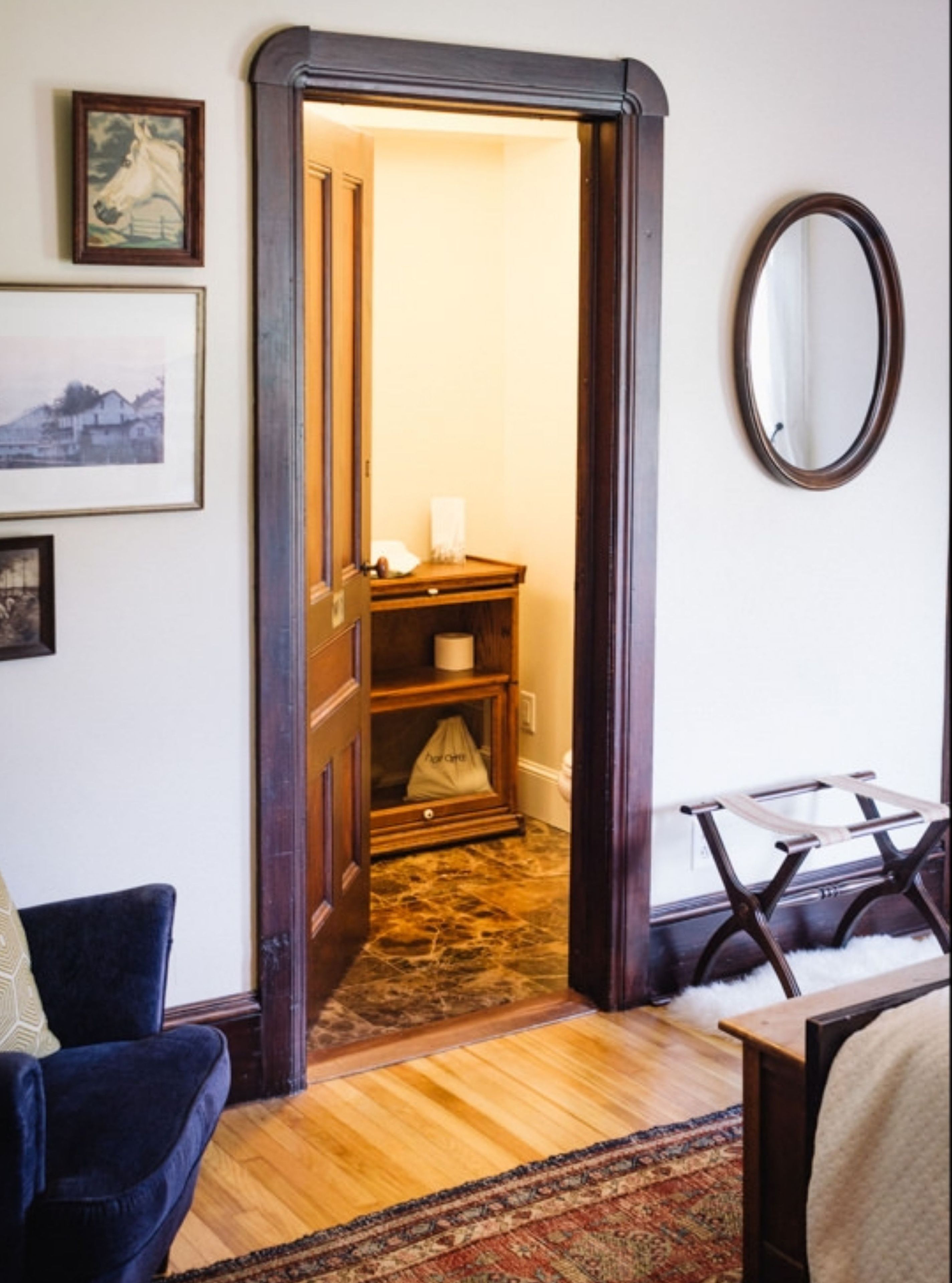 A doorway leading to a bathroom with a wooden door, a towel rack, and a mirror on the wall.