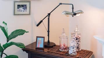 A wooden desk with a desk lamp, a picture frame, and two glass jars with decorative items.