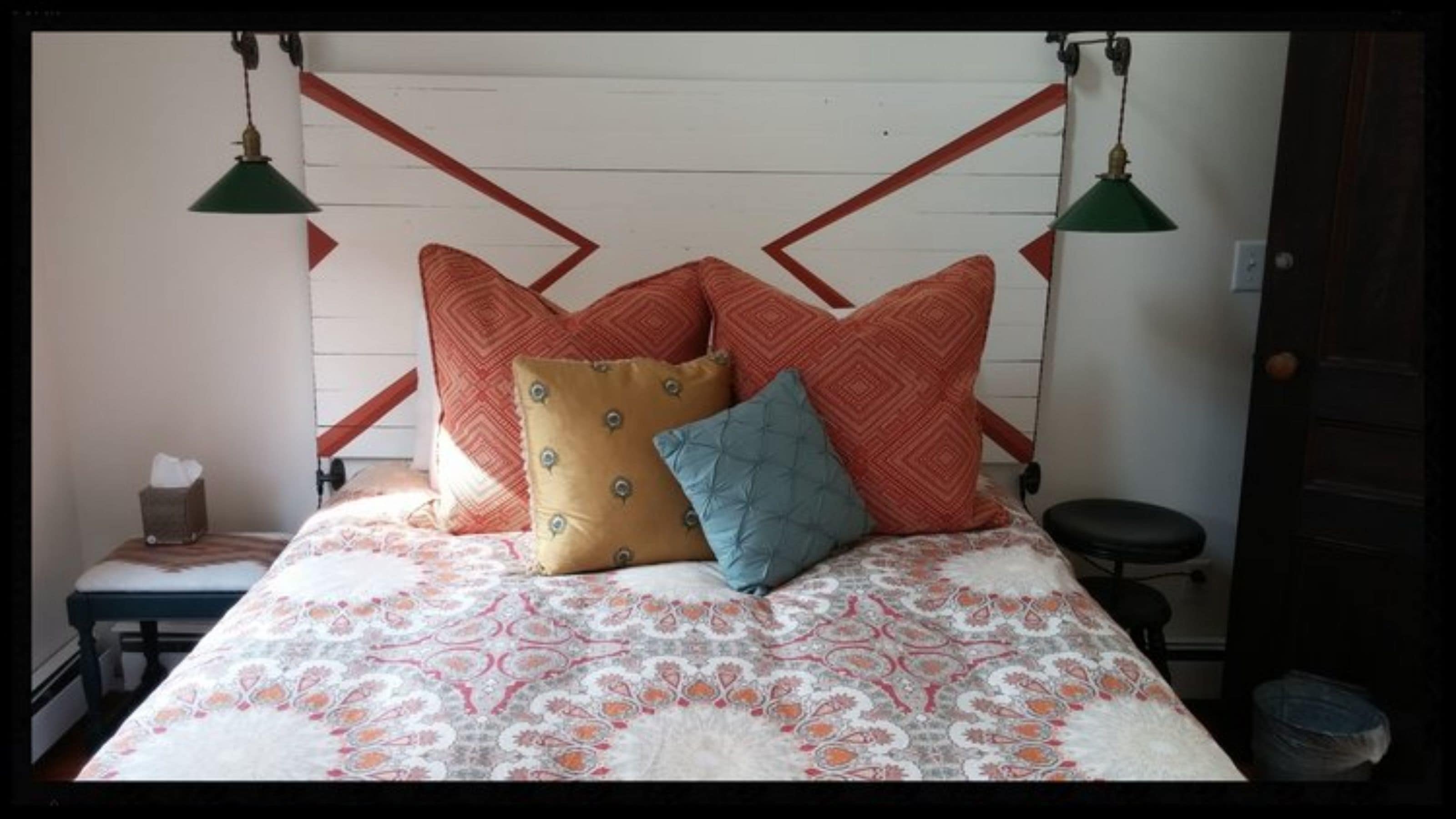 Un letto con biancheria decorata, due cuscini e due lampade a sospensione.