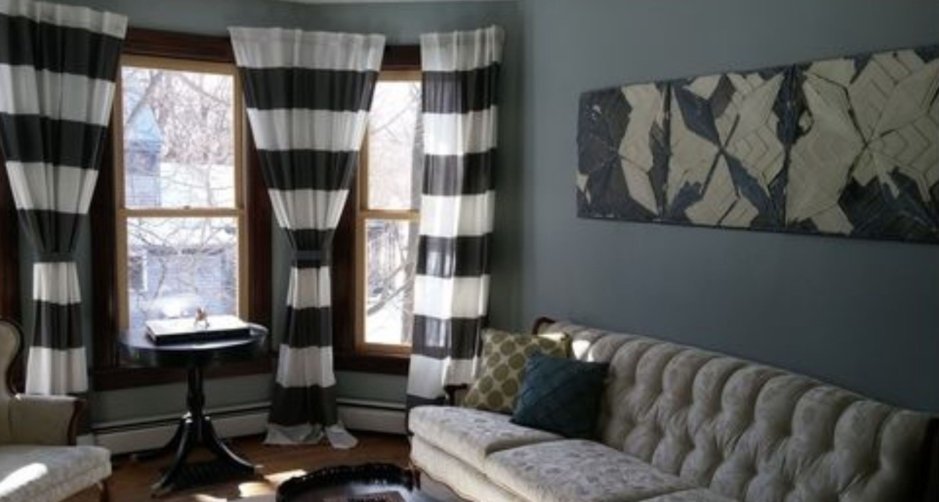 A living room with a sofa, a table, and striped curtains.