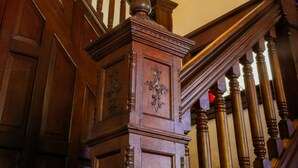 A wooden staircase with a balustrade and a small stained glass window. - Burdett House Bed & Breakfast (Burdett)