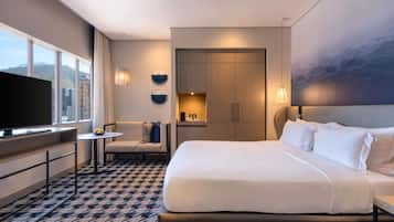 A hotel room with a large bed, a television, a seating area, and a view of the outdoors.