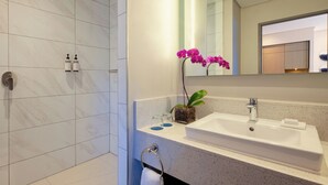 Un baño moderno con ducha, lavabo y espejo.