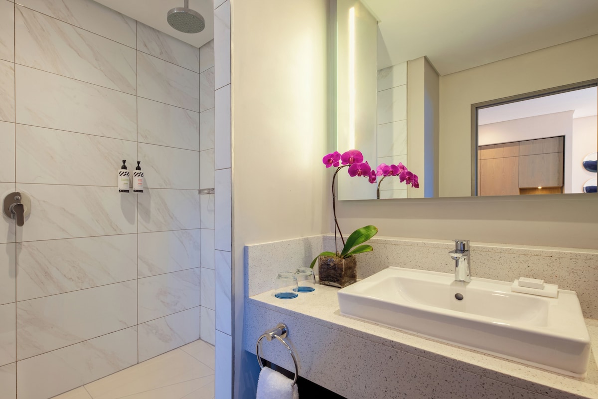 Un baño moderno con ducha, lavabo y espejo.