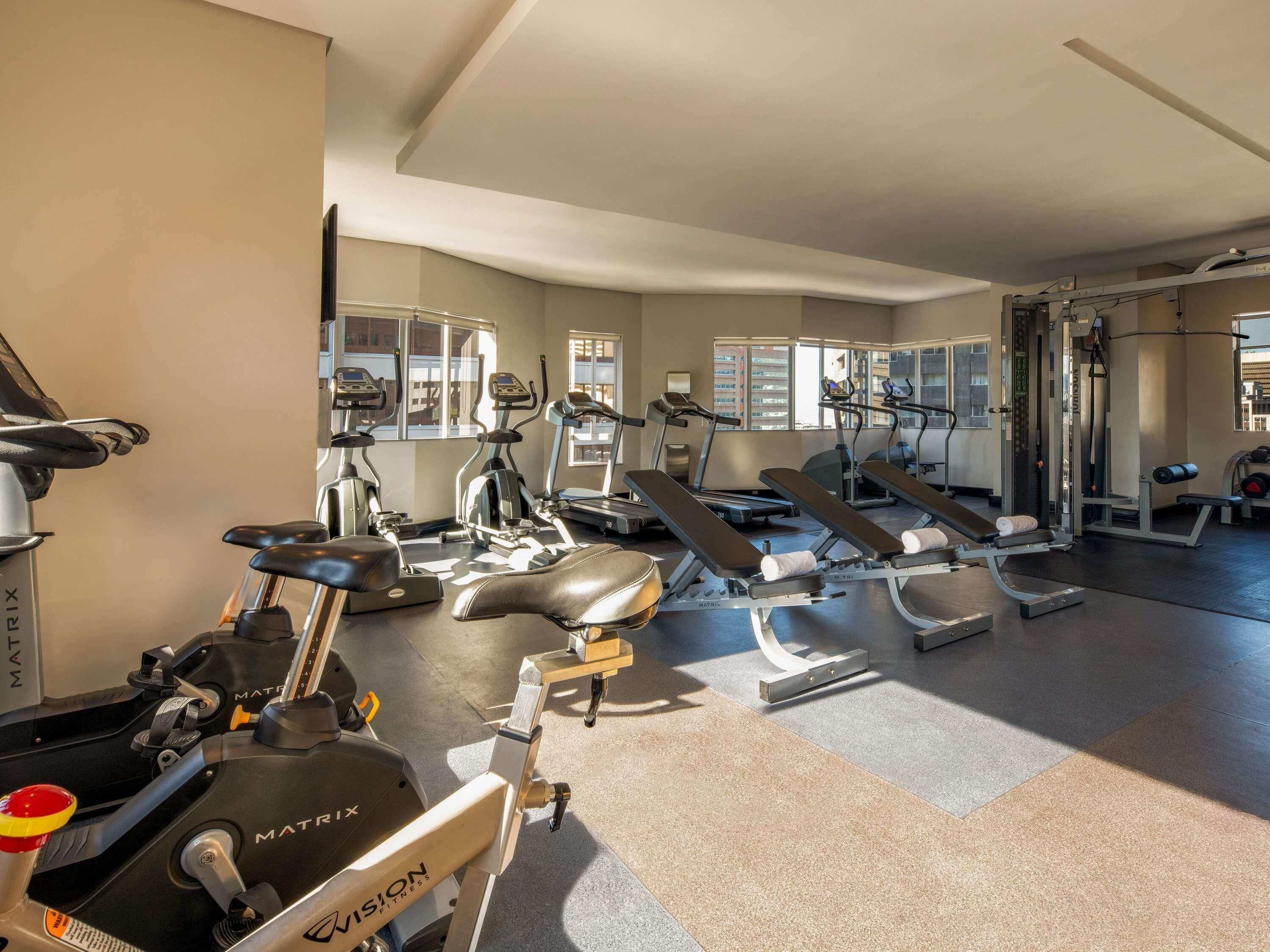 A gym with various exercise equipment including treadmills, elliptical machines, and weight benches.