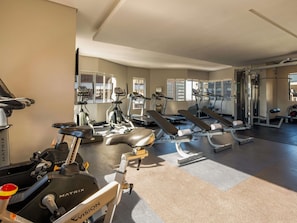 Un gimnasio con diversos equipos de ejercicio, incluyendo cintas de correr, elípticas y bancos de pesas.