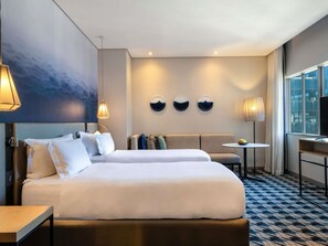 A hotel room with a large bed, a sofa, a small table, and a TV. - Pullman Cape Town City Centre (Cape Town)