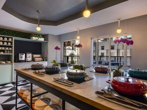 A modern kitchen with a long counter, coffee machines, and potted plants. - Pullman Cape Town City Centre (Cape Town)