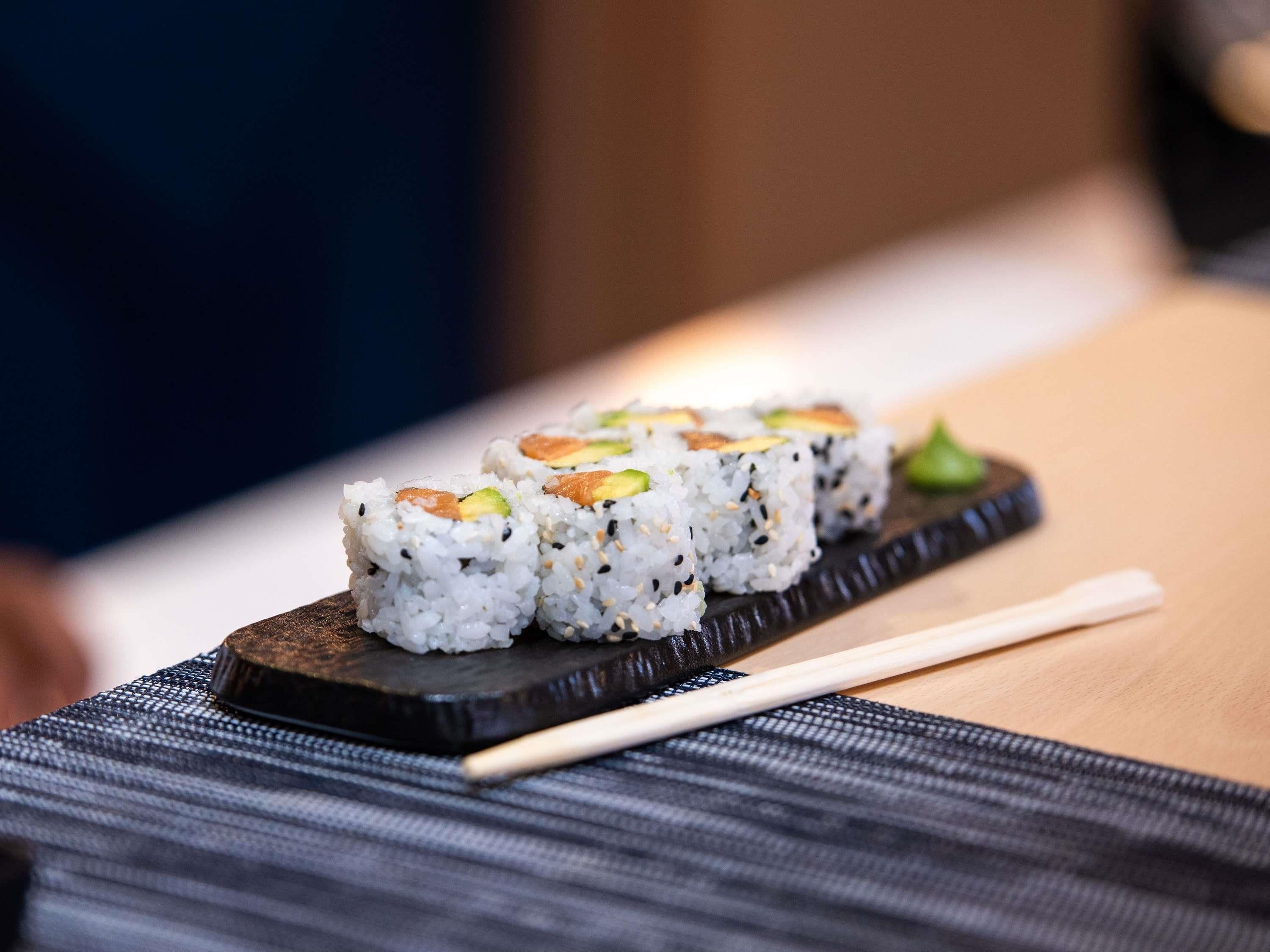 Sushi on a wooden board with chopsticks.