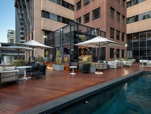A rooftop bar with outdoor seating, a pool, and a building with large windows. - Pullman Cape Town City Centre (Cape Town)