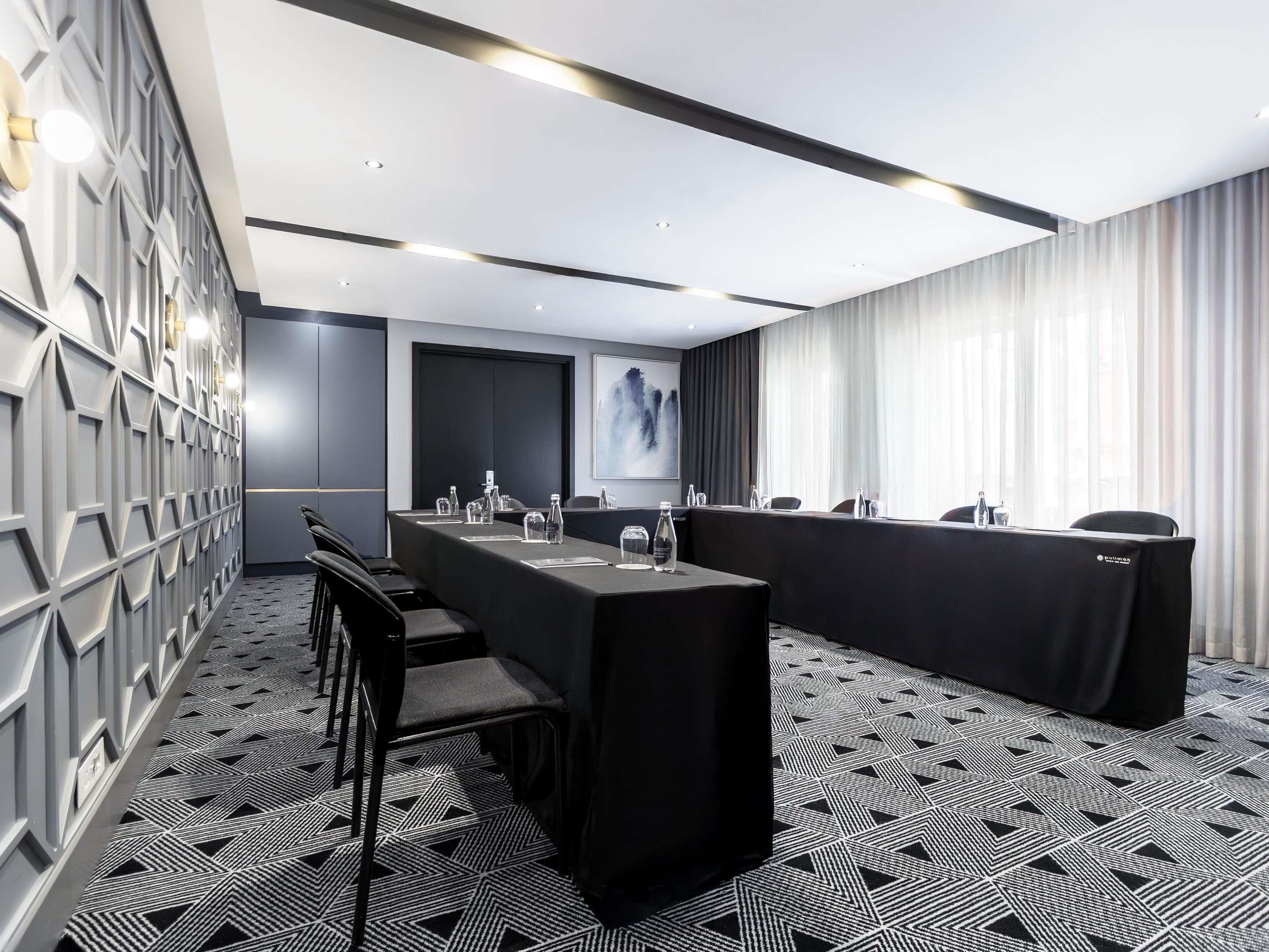 Un salón de conferencias con una larga mesa, sillas y un cuadro grande en la pared.