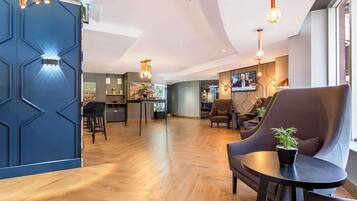 Un moderno vestíbulo de hotel con piso de madera, paredes de acento azul y mobiliario contemporáneo.