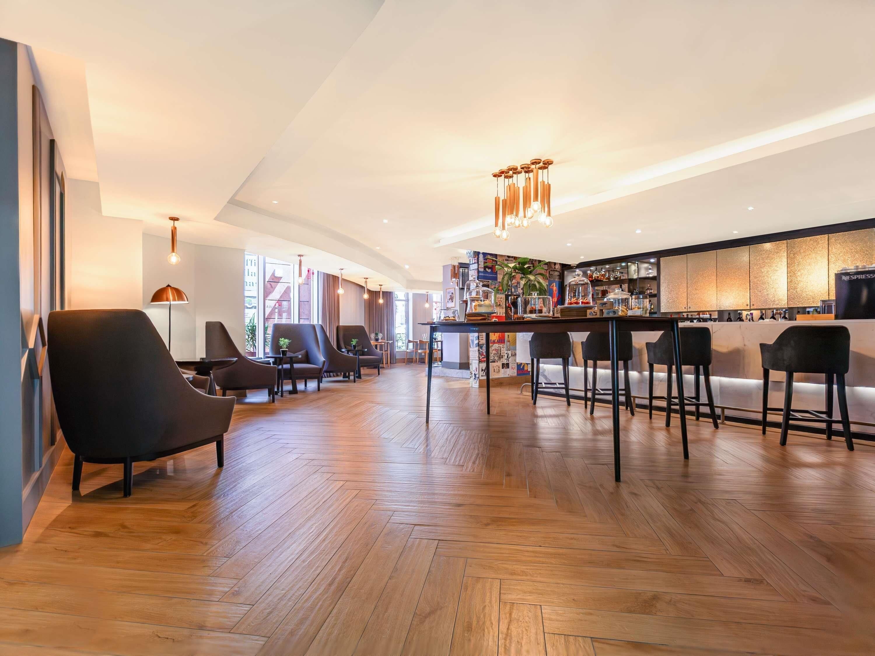 A modern bar area with wooden flooring, black bar stools, and a Nespresso machine.