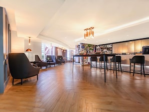 Una zona de bar moderna con suelo de madera, taburetes negros y una máquina Nespresso.