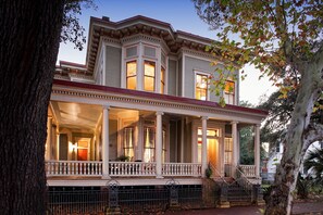 A two-story house with a porch, columns, and a red roof.