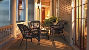 A porch with wicker chairs, a small table, and a potted plant.