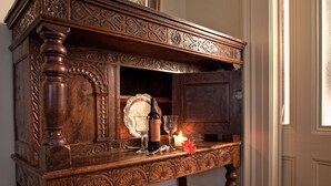 An ornate wooden sideboard with a wine bottle, glasses, and a candle.