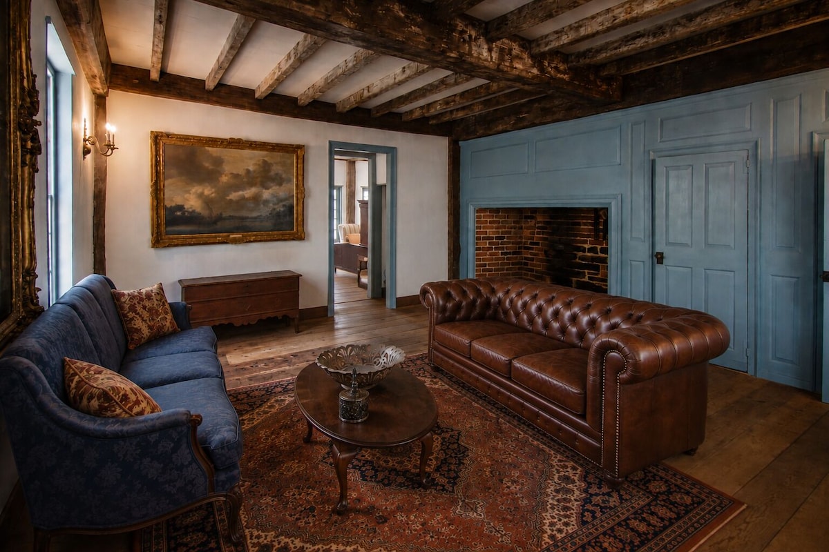 A room with a blue sofa, a brown leather couch, a patterned rug, and a fireplace.