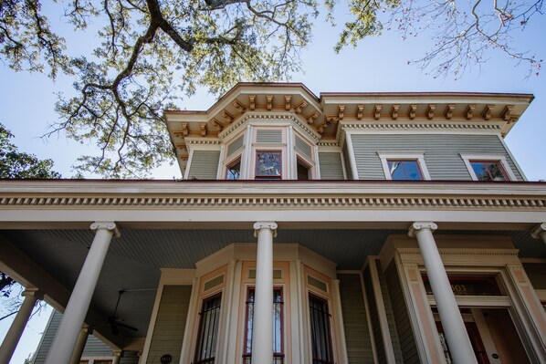 A two-story house with a balcony, columns, and a bay window.