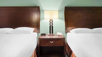A hotel room with two single beds, a nightstand with a lamp, a telephone, and a small table.