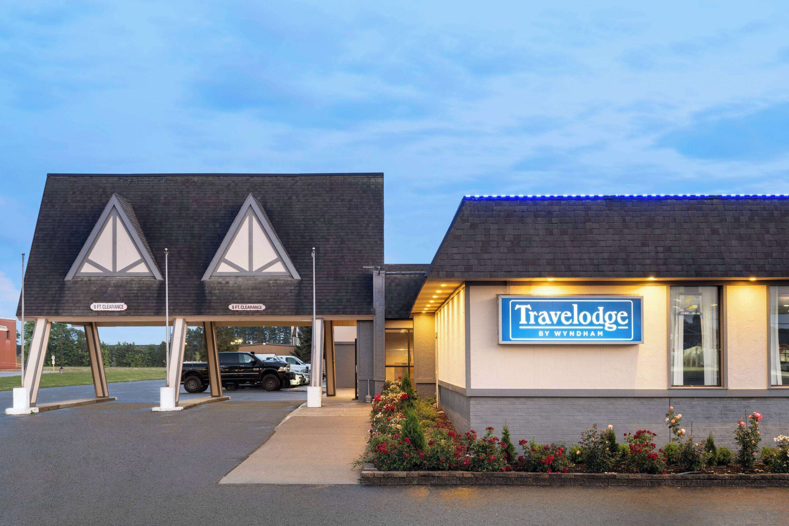 Un hotel Travelodge by Wyndham con un diseño arquitectónico distintivo, que incluye un techo triangular y un cartel.