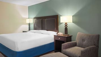 A hotel room with a large bed, two bedside tables with lamps, a chair, and a small table.