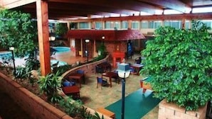 An indoor area with a pool, seating, and greenery.