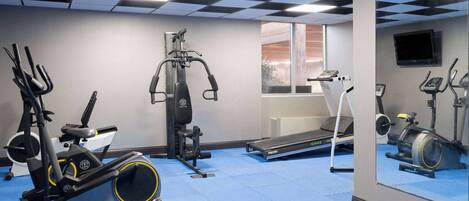 A gym with various exercise equipment, a treadmill, and a mirrored wall.