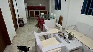 A living room with a sofa, chairs, a coffee table, and a small dog. - Apartamentos Katy (San Andrés)