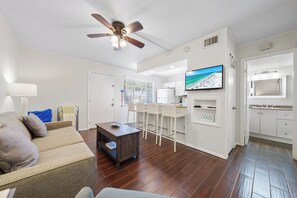 A modern living room with a sofa, coffee table, and a TV mounted on the wall. - Sea Club II by Beachside Management (Siesta Key)