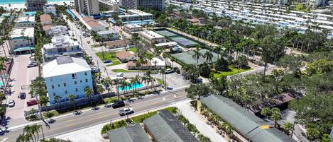 A coastal resort area with multiple hotel buildings, a swimming pool, and a beach in the background.