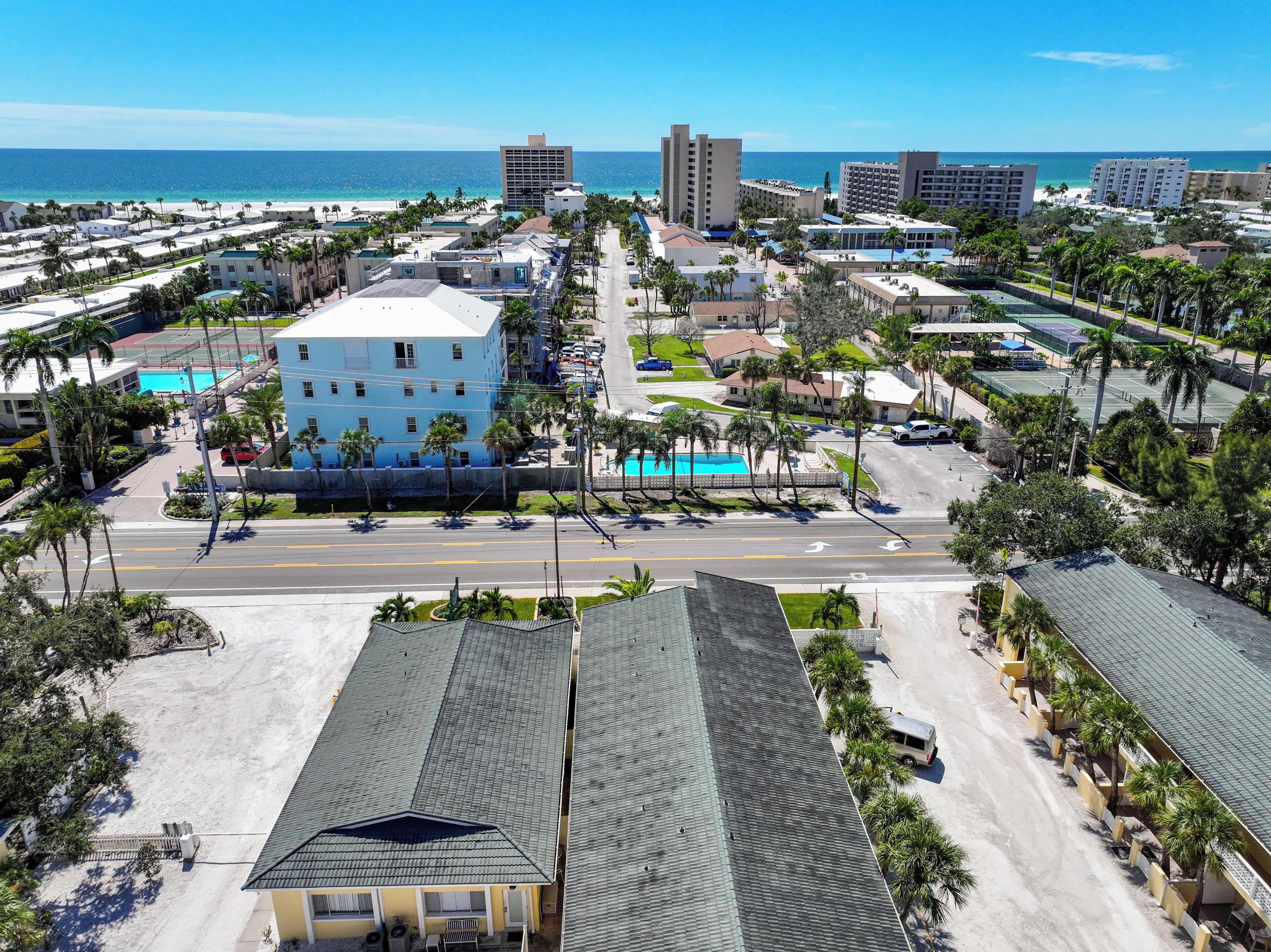 A coastal resort area with multiple buildings, a road, and a beach in the background.
