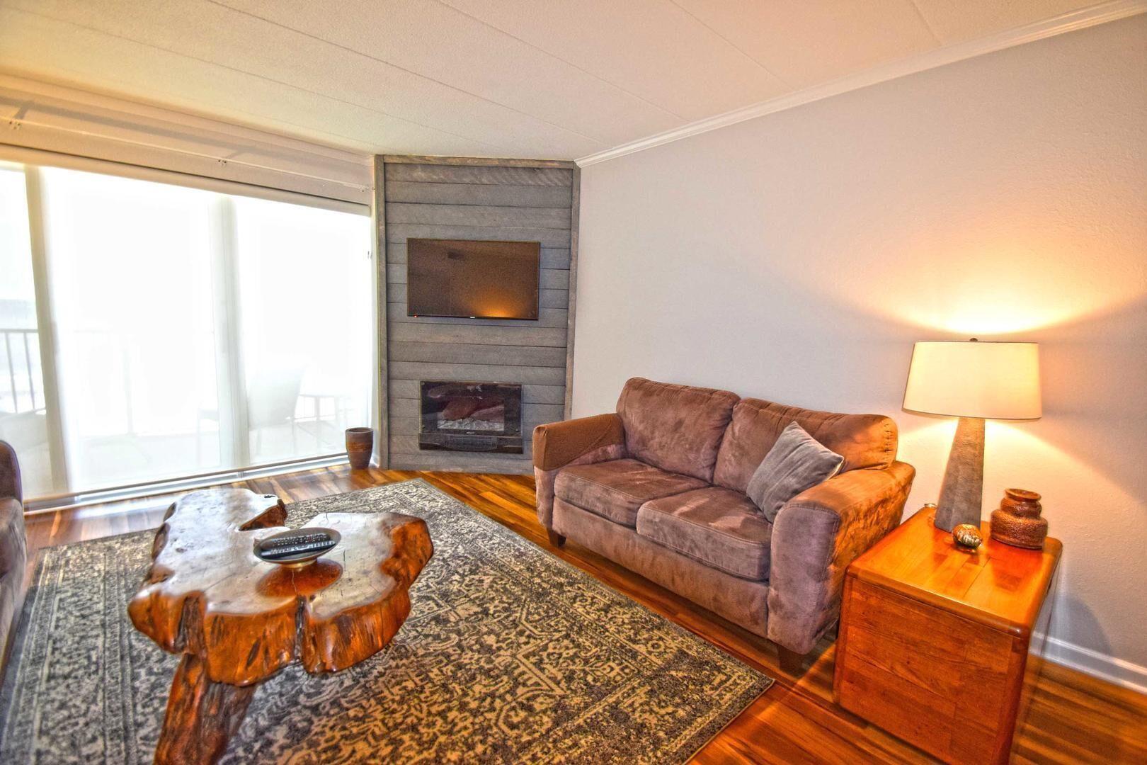 Ein gemütliches Wohnzimmer mit einer Couch, einem Couchtisch, einem Kamin und einer Lampe.
