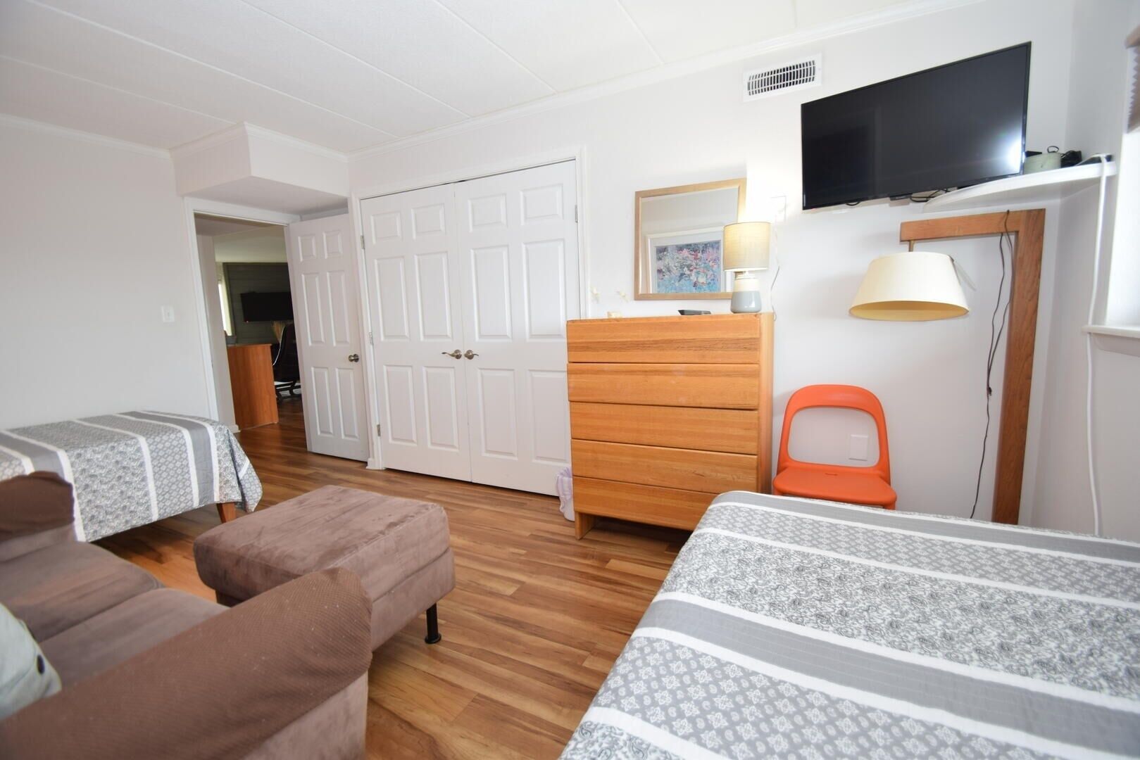 Una habitación con dos camas, un tocador, un televisor y una puerta.