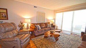 A living room with a leather sofa, a wooden coffee table, and a patterned rug.