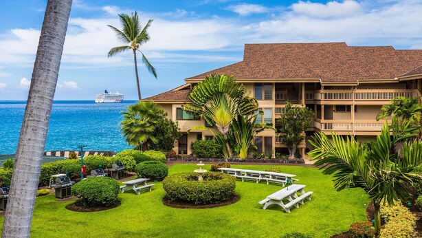 A hotel with a pool, palm trees, and a view of the ocean.