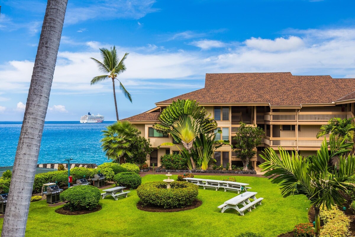 A hotel with a pool, palm trees, and a view of the ocean.