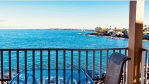 A balcony with a clear view of the ocean and a distant shoreline.