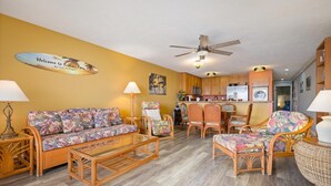 A living room with a sofa, chairs, a coffee table, and a ceiling fan.