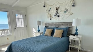 A bedroom with a large bed, a nightstand with a lamp, and a decorative wall hanging. - Eastside  3 Bedroom Home by RedAwning (Supply)