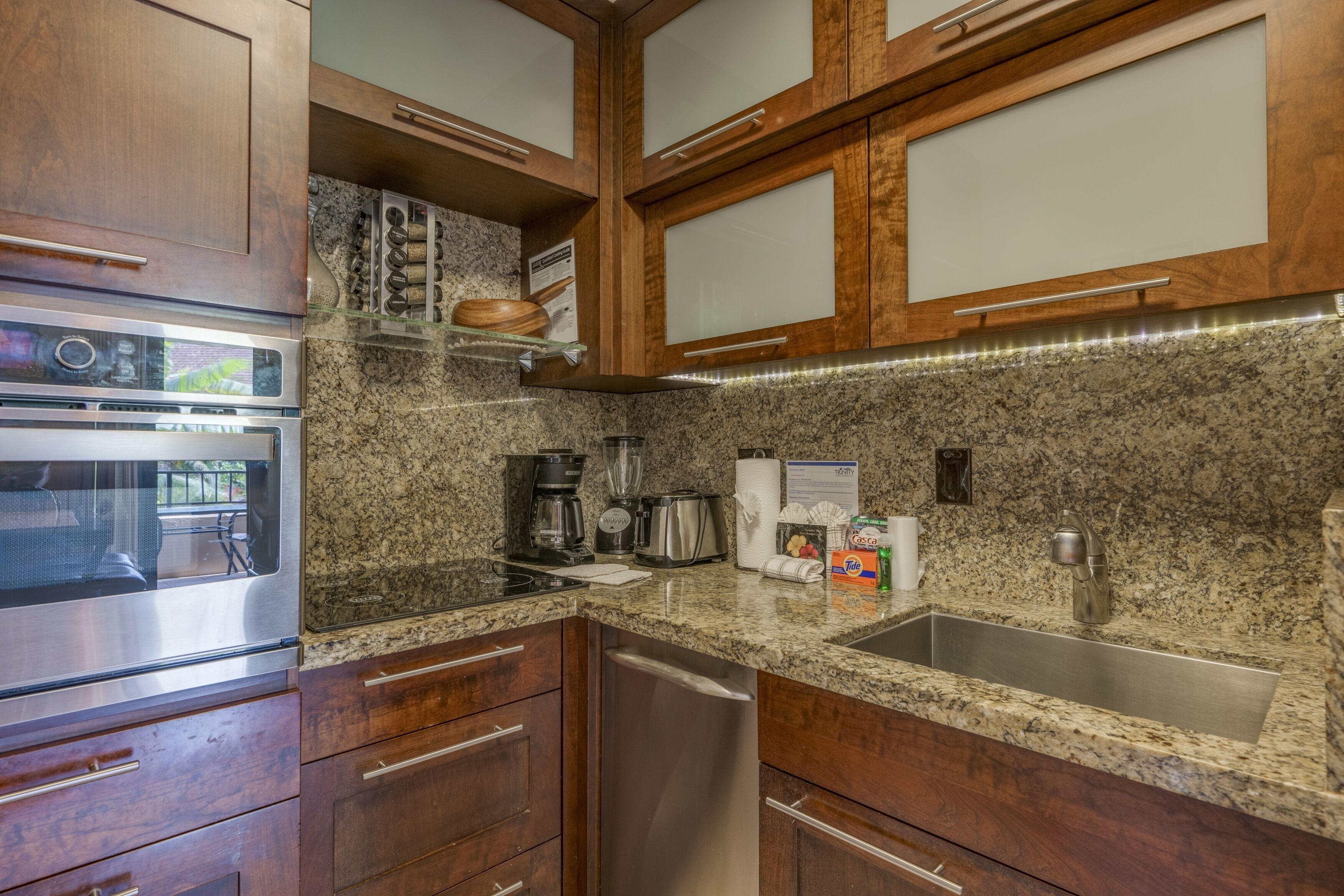 A kitchen with granite countertops, stainless steel appliances, wooden cabinets, and a built-in dishwasher.