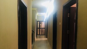 Un pasillo estrecho con piso de baldosas, que conduce a una puerta con un panel de vidrio.