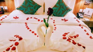 En pænt redt seng med rosenblade arrangeret i et hjerteformet mønster og en enkelt rose i midten.