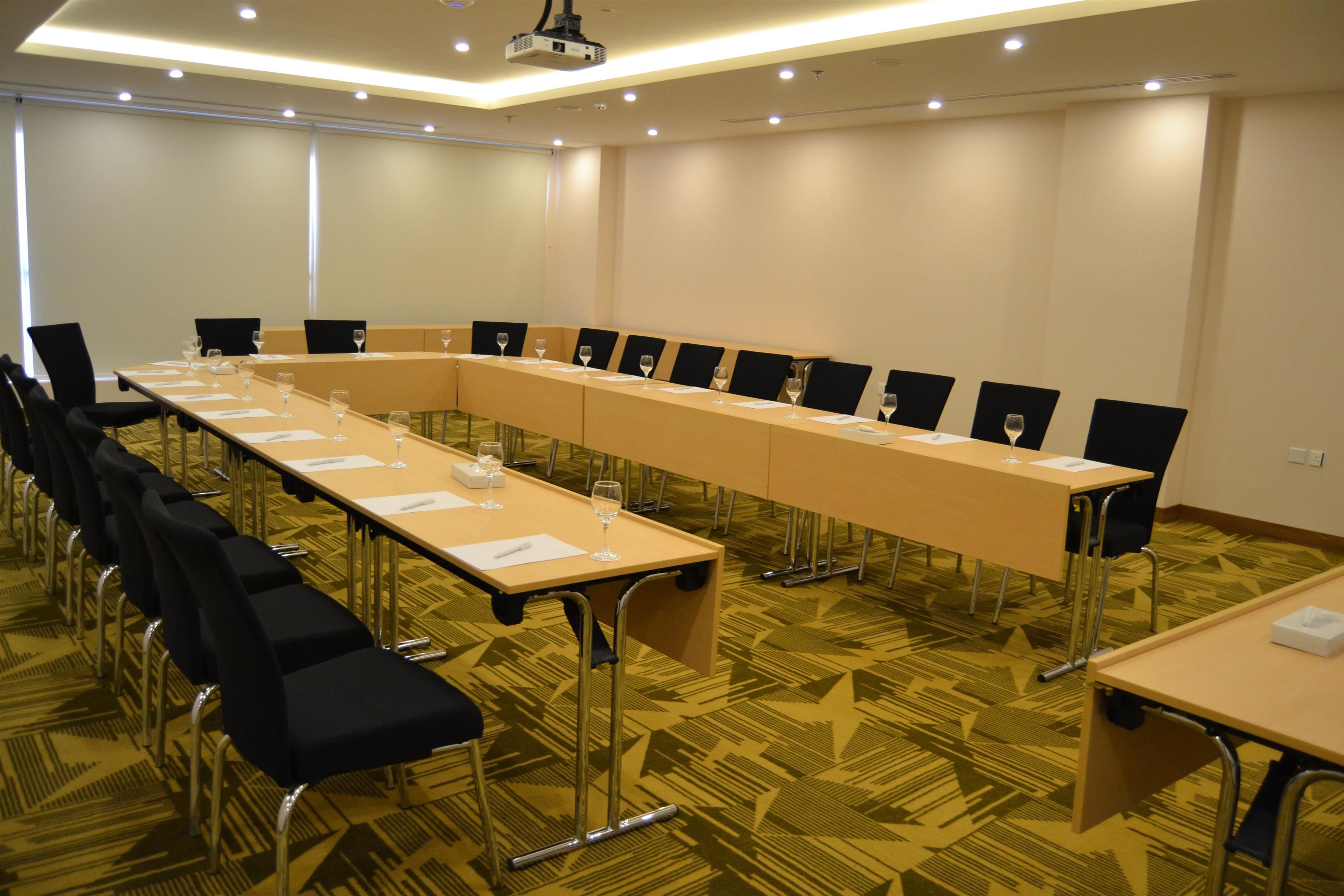 A conference room with a long table, chairs, and a projector.