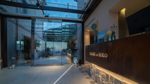 Een moderne hotellobby met glazen entree, een receptiebalie en uitzicht op de omgeving.